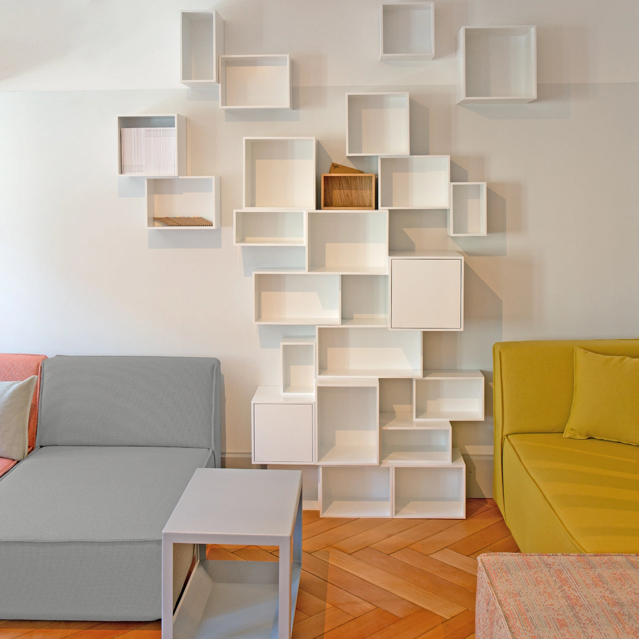 Modulares Cubit Regal in Weiß als Wandinstallation im Zürcher Lookroom, kombiniert mit farbigen Sofa-Modulen und kleinem Beistelltisch
