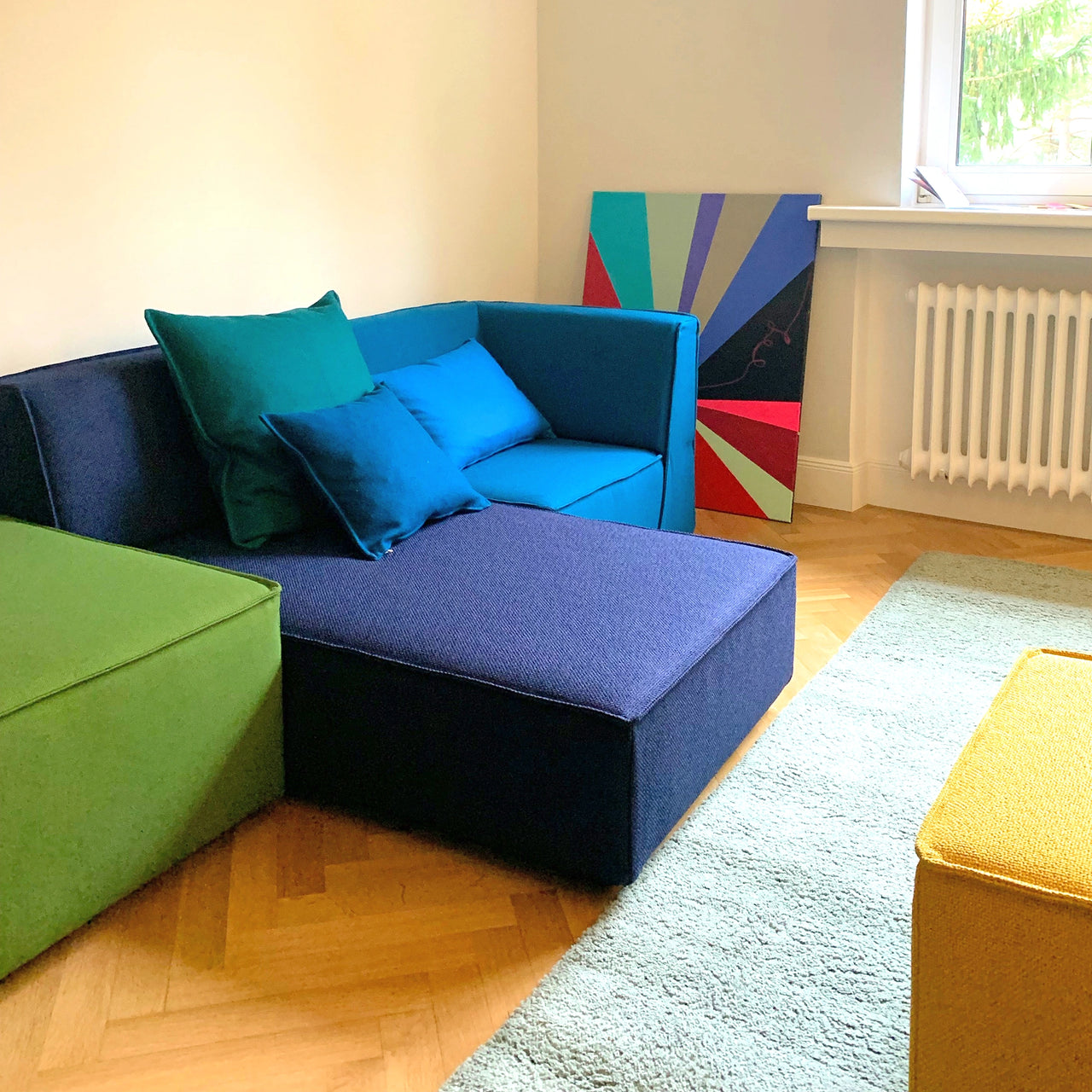 colour-coordinated Cubit sofa modules in green, blue and yellow with cushions in the Munich Showroom , on parquet flooring with carpet