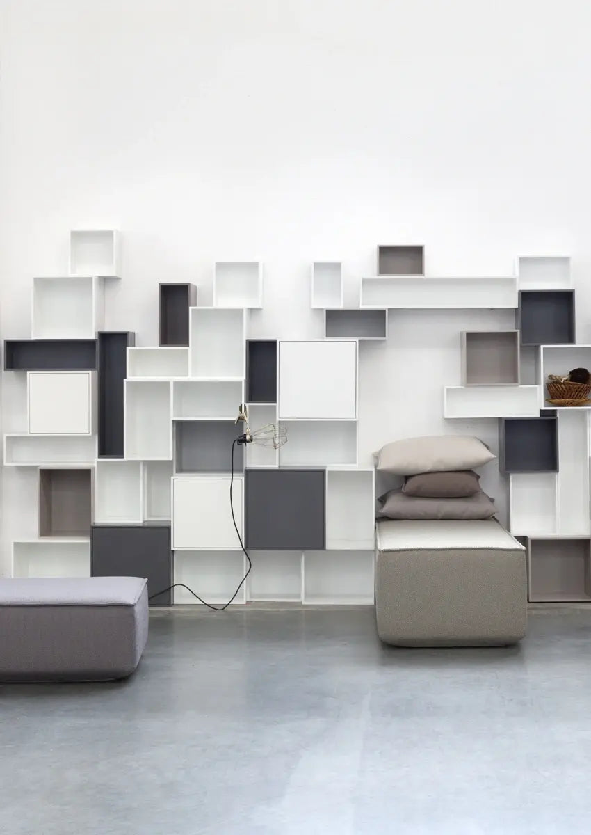 Système d'étagères modulaires Système d'étagères et blanc sur le mur du salon, avec des canapés modulaires gris.