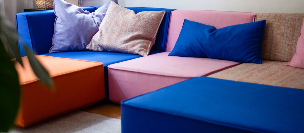 Gros plan canapé modulable , orange et rose, agrémenté de coussins colorés, dans le salon.