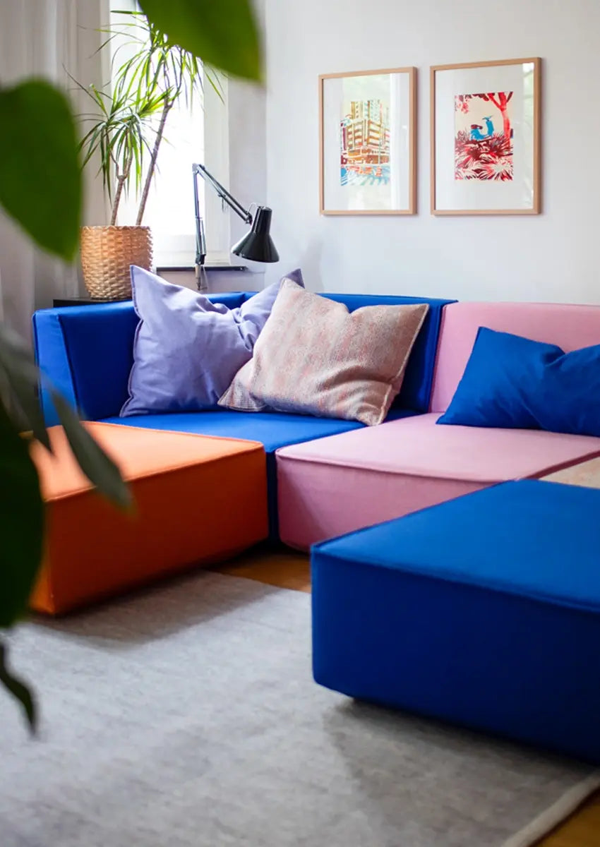 Gros plan sur des coussins de canapé modulaires colorés, bleus, orange et roses, avec des coussins.
